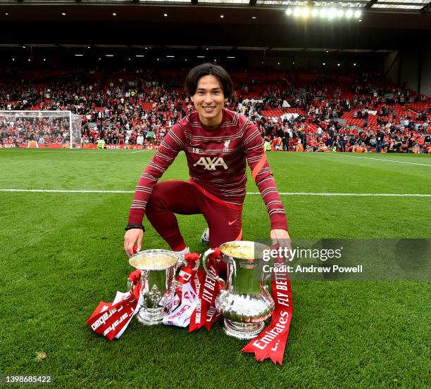 Takumi Minamino of Liverpool posing with the Emirates FA Cup and the Carabao Cup at the end of the Premier League match between Liverpool and...