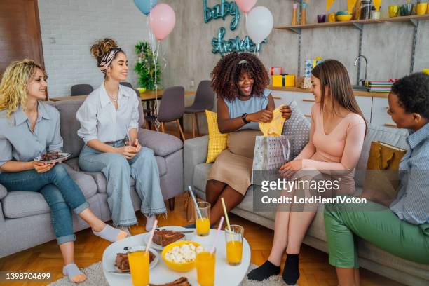 holding baby clothes during a baby shower - babyshower stockfoto's en -beelden