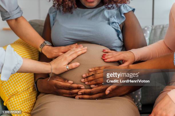 hands on stomach of pregnant woman - baby shower party stock pictures, royalty-free photos & images