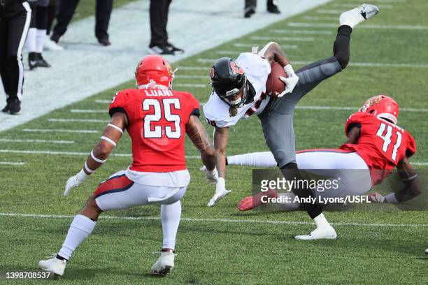 Teo Redding of the Houston Gamblers trips over De'Vante Bausby of the New Jersey Generals as Shalom Luani defends in the second quarter of the game...
