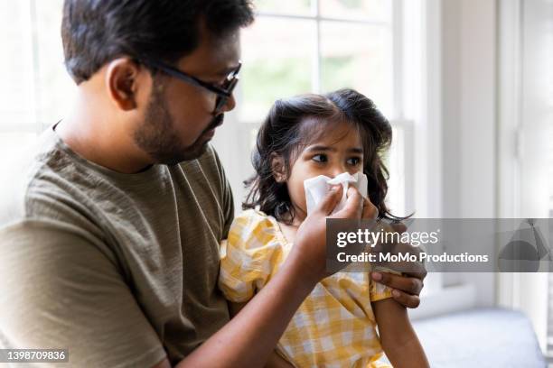 father wiping toddler daughters nose - grippe krank stock-fotos und bilder