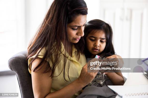 mother putting bandage on toddler daughter - family hugging bright stockfoto's en -beelden