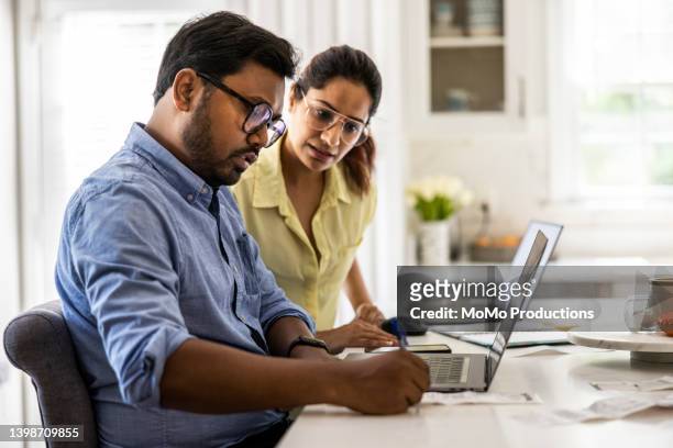 husband and wife using laptop computers in kitchen - indian economy stock pictures, royalty-free photos & images