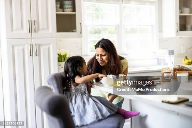 mother making a sandwich for toddler daughter in kitchen - indian mother daughter stock pictures, royalty-free photos & images