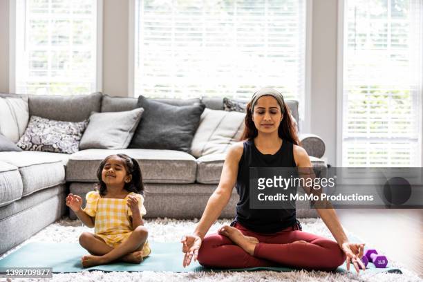 mother and toddler daughter meditating at home - yoga rug photos et images de collection