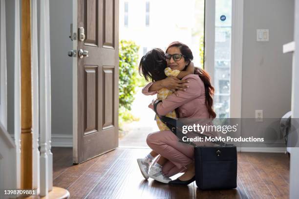 toddler girl embracing mother in doorway as she gets home from work - terugkomen stockfoto's en -beelden