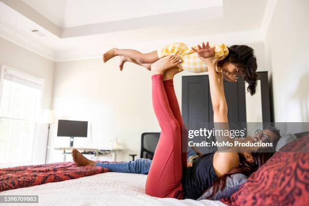 mother holding toddler daughter in the air with her feet - family with one child mother bonding family adult daughter focus on background leisure stock-fotos und bilder