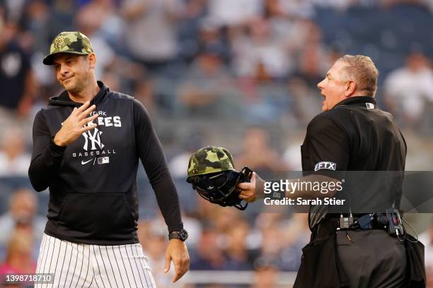 Manager Aaron Boone of the New York Yankees talks with umpire Greg Gibson after pitching coach Matt Blake was ejected during the third inning of Game...