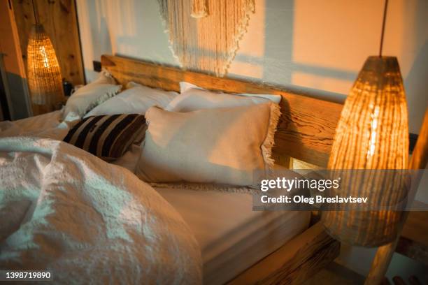 evening romantic mood in bedroom. stylish room with handmade design elements in boho style. beautiful light in cozy home. - manta-ropa-de-cama fotografías e imágenes de stock