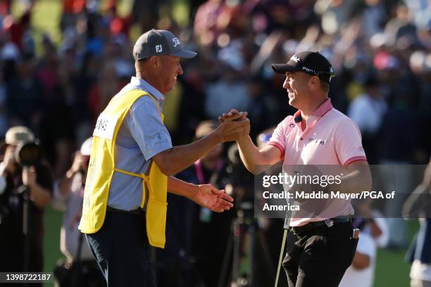 Justin Thomas of the United States reacts to his winning putt on the 18th hole with caddie Jim "Bones" Mackay, the third playoff hole during the...