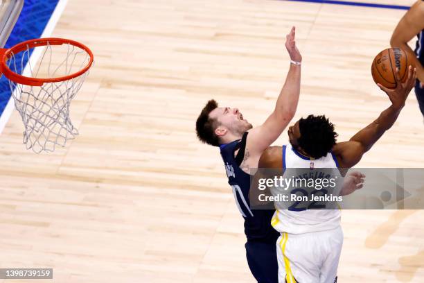 Andrew Wiggins of the Golden State Warriors dunks the ball against Luka Doncic of the Dallas Mavericks during the fourth quarter in Game Three of the...