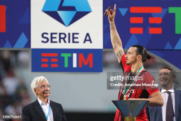 Zlatan Ibrahimovic of AC Milan acknowledges the fans as he celebrates smoking a cigar on the winners' podium following the Serie A match between US...