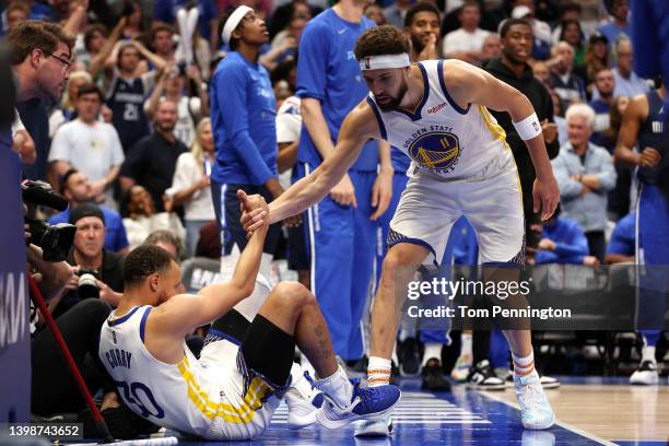 Klay Thompson of the Golden State Warriors helps up teammate Stephen Curry during the fourth quarter against the Dallas Mavericks in Game Three of...