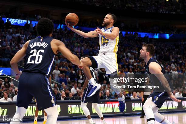 Stephen Curry of the Golden State Warriors drives to the basket against Spencer Dinwiddie and Luka Doncic of the Dallas Mavericks during the fourth...