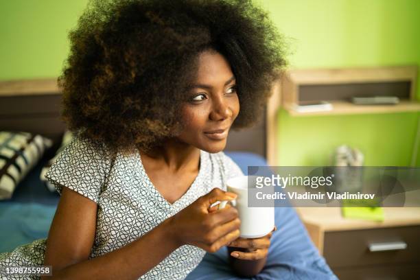 close up of a woman holding coffee mug lying in bed - enjoying coffee stock pictures, royalty-free photos & images
