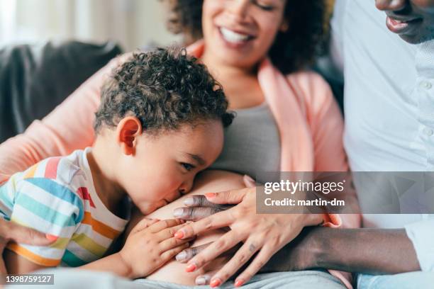 pregnant woman with husband and son at home - belly kissing stock pictures, royalty-free photos & images