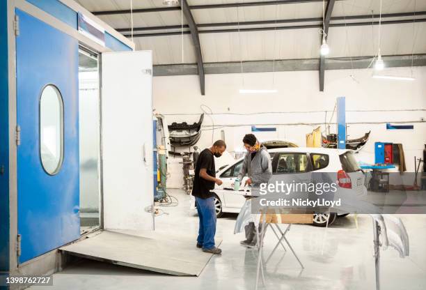 mecánico discutiendo con un colega en el taller de servicio de automóviles - abollado fotografías e imágenes de stock