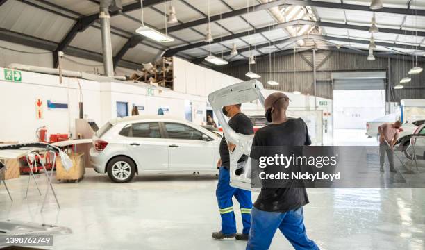 two mechanics working in auto repair shop moving car parts - car bodywork stock pictures, royalty-free photos & images