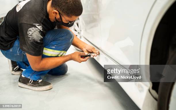 auto mechanic removing a dent from car surface at garage - carrosserie stockfoto's en -beelden