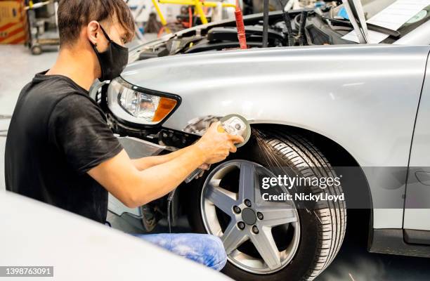 mechanic repairing dent on a car body at auto service center - slijptol stockfoto's en -beelden