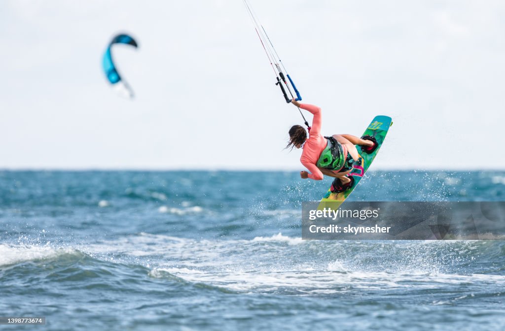 Rear view of a woman jumping during kiteboard surfing at sea.