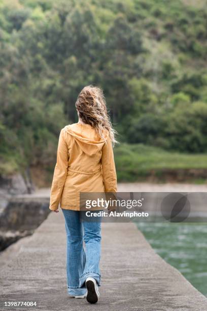 young woman on her back connecting with nature in a harbor by the sea. concept of relaxation and freedom. - paisaje no urbano stock-fotos und bilder