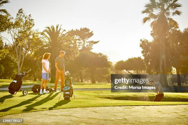 golfers practicing at sports field in summer - バンカーショット ストックフォトと画像