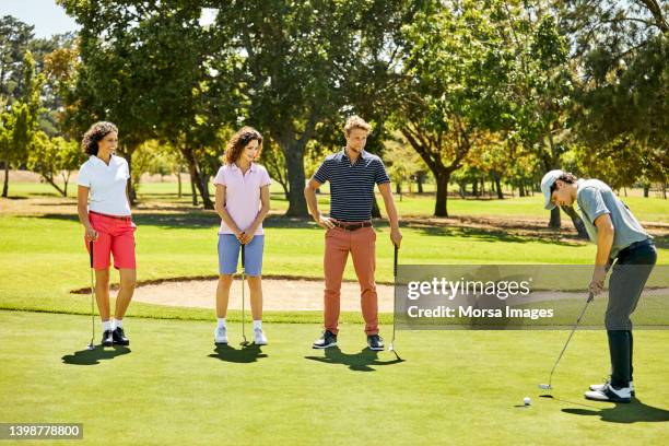 golfers practicing at sports field in summer - golf putter stock pictures, royalty-free photos & images