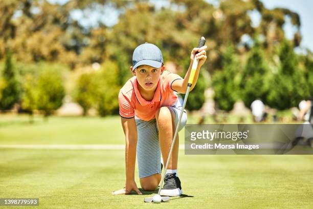 golfer kneeling while planning putt on field - young golfer stock pictures, royalty-free photos & images