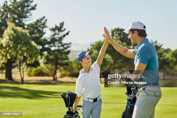 happy golfer giving high-five to son on golf field - golf pro stock pictures, royalty-free photos & images