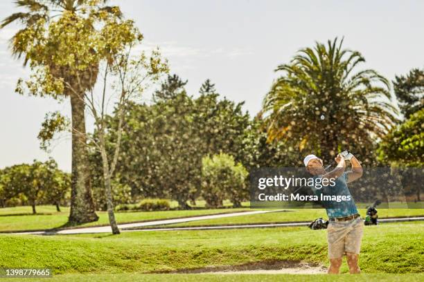 male golfer playing golf during sunny day - bunker campo da golf - fotografias e filmes do acervo