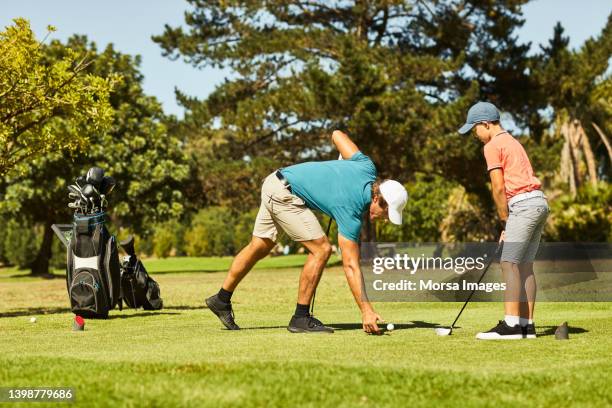 boy learning golf from father on field in summer - golf lessons stock pictures, royalty-free photos & images