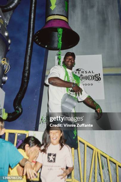 Children laugh as American basketball player Shaquille O'Neal with a large whistle hanging around his neck is covered with green slime at the 1997...