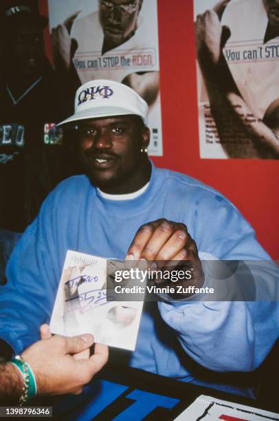 American basketball player Shaquille O'Neal, wearing a light blue sweatershirt and a white visor, attends a signing event for his single 'You Can't...
