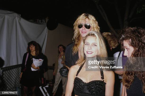 American guitarist and songwriter Duff McKagan and his partner, Mandy Brixx, wearing a black bra top, attend the 1989 MTV Video Music Awards, held at...