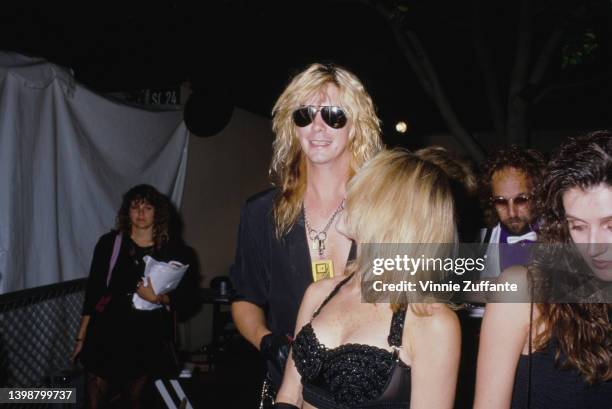 American guitarist and songwriter Duff McKagan and his partner, Mandy Brixx, wearing a black bra top, attend the 1989 MTV Video Music Awards, held at...