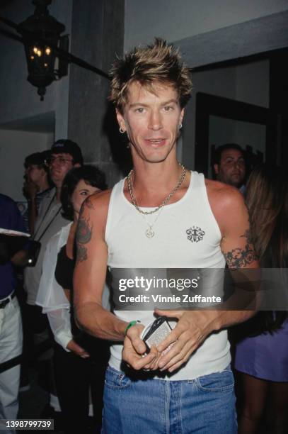 American guitarist and songwriter Duff McKagan, wearing a white singlet with blue jeans attends an event, United States, 1996.