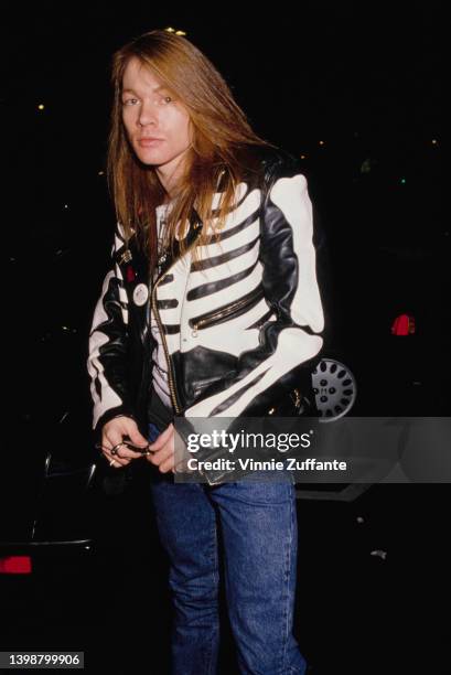 American singer and songwriter Axl Rose, wearing a black leather jacket with a print of the torso of a human skeleton in white, attends an Andrew...