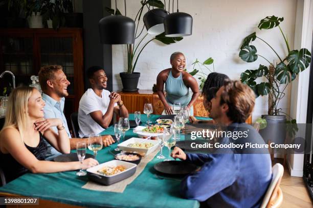 une jeune femme qui rit organise un dîner pour un groupe d’amis - inviter photos et images de collection