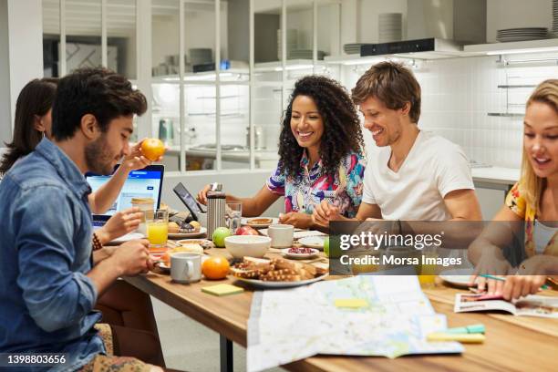 friends planning trip while having meal at hostel - bed and breakfast foto e immagini stock