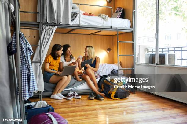 friends planning trip on bunkbed in dorm room - hostel stock pictures, royalty-free photos & images