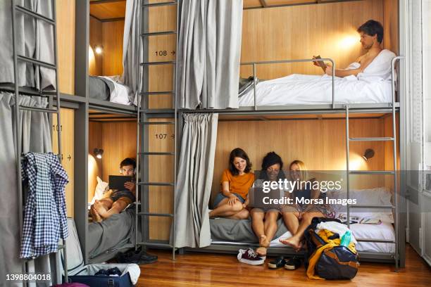 male and female friends resting in dorm room - hostel stock pictures, royalty-free photos & images