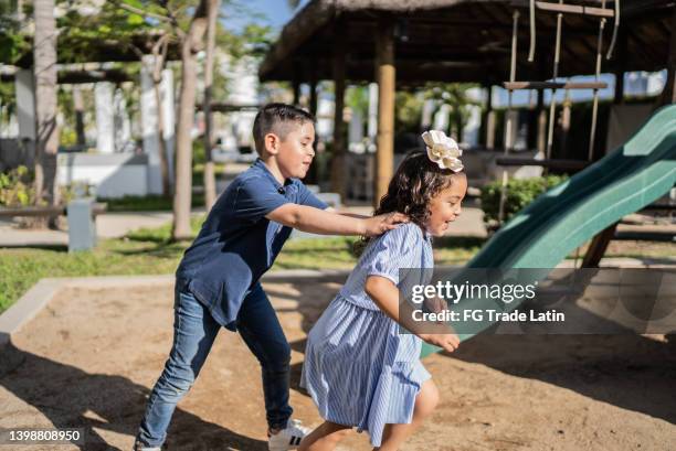 hermanos jugando en un patio de recreo - kids playing tag fotografías e imágenes de stock