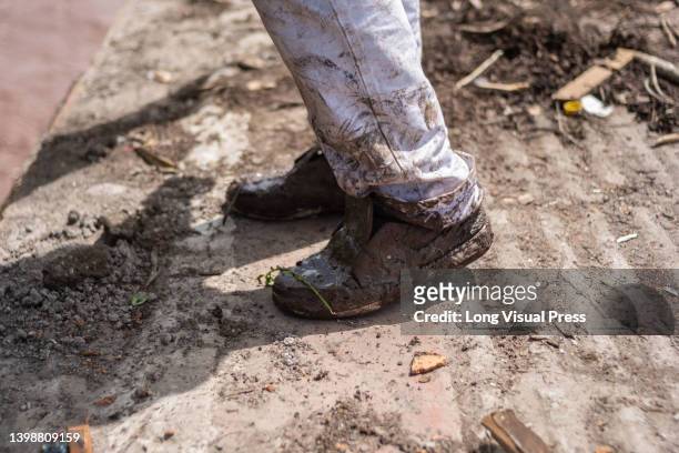 Man with his shoes covered in mud is seen as people of Villavicencio, Colombia react and stay in shelters after the Guatiquia river overflowed its...