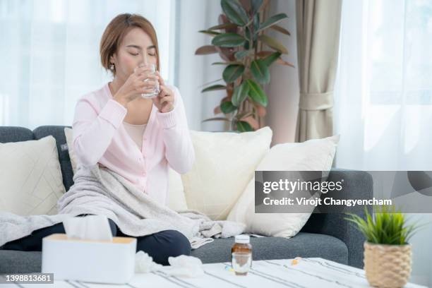 sick woman with high fever taking medicine at home - slaappil stockfoto's en -beelden