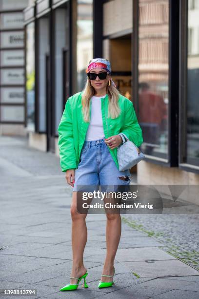 Sonia Lyson is seen wearing green heels Amina Muaddi, denim shorts Storets, green bomber jacket Rotate, blue bag, head scarf, earrings, sunglasses...