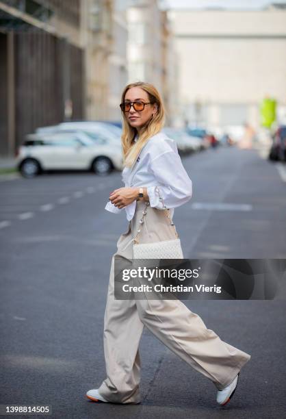 Sonia Lyson is seen wearing sneaker New Balance, beige high waist pants The Frankie Shop, white button shirt Miu Miu, bag Miu Miu, sunglasses Vehyla...