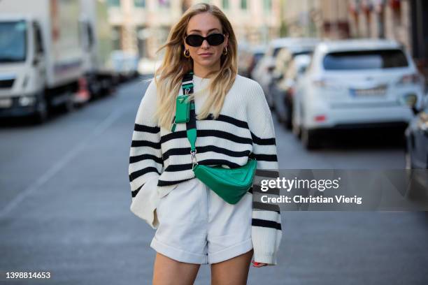 Sonia Lyson is seen wearing striped black white jumper &other stories, green Prada triangle bag, Prada loafers, white leather shorts Rotate, Celine...