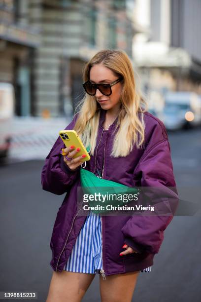 Sonia Lyson is seen wearing green bag, black heels Prada, blue white striped shorts Monki, top Zara, Isabel Marant sunglasses, burgundy bomber jacket...