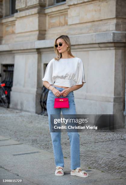 Mandy Bork is seen wearing Agolde Jeans, Chanel sandals, red Hermes bag, Ray Ban sunglasses, Vero Moda backless blouse on May 22, 2022 in Berlin,...